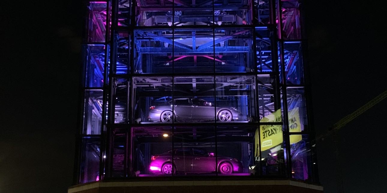 An 8 story Carvana sales tower at night light up with neon