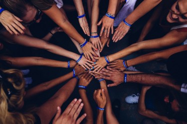 A group of hands on top of one another in the center of a circle