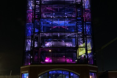 An 8 story Carvana sales tower at night light up with neon